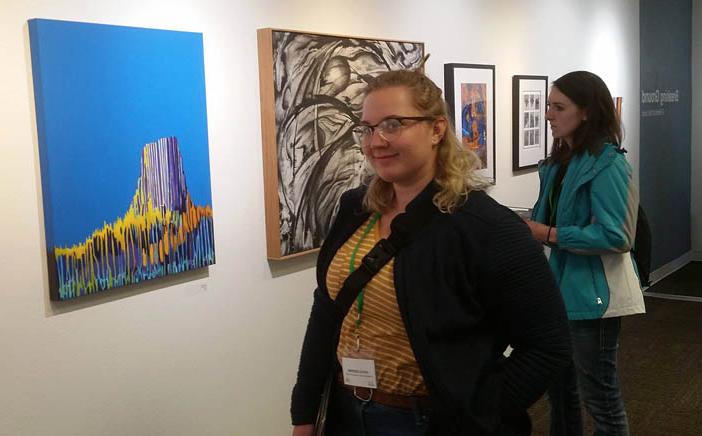 Two students view paintings on a wall